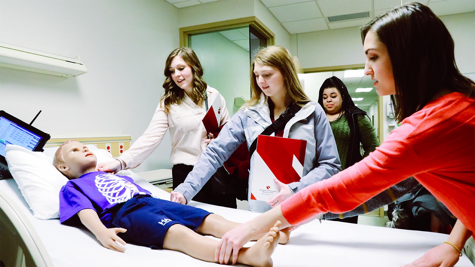 students learning to administer care to child manikin